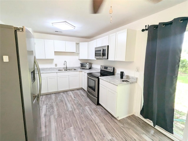 kitchen featuring sink, white cabinets, light wood-type flooring, and stainless steel appliances