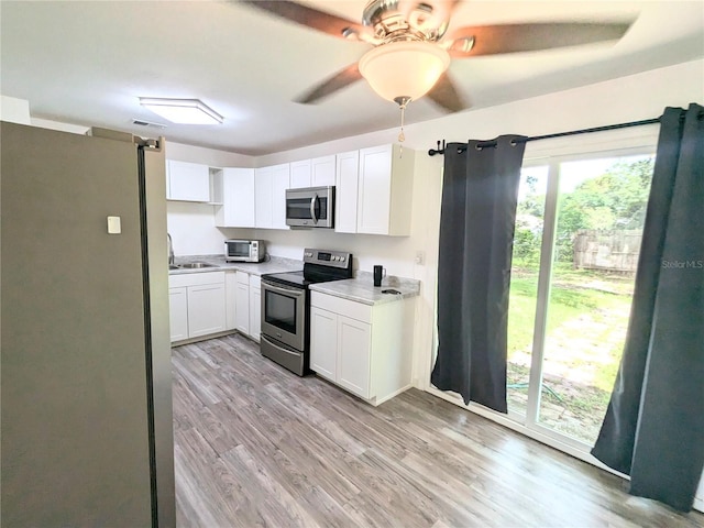 kitchen featuring white cabinetry, stainless steel appliances, light hardwood / wood-style floors, sink, and ceiling fan