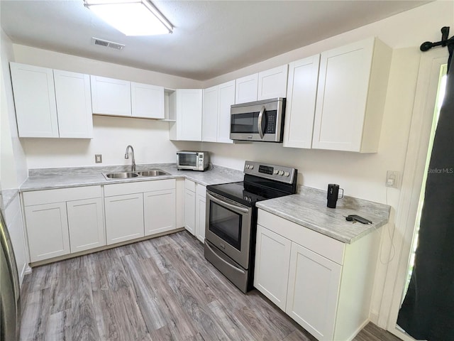 kitchen featuring light hardwood / wood-style floors, sink, white cabinets, and stainless steel appliances