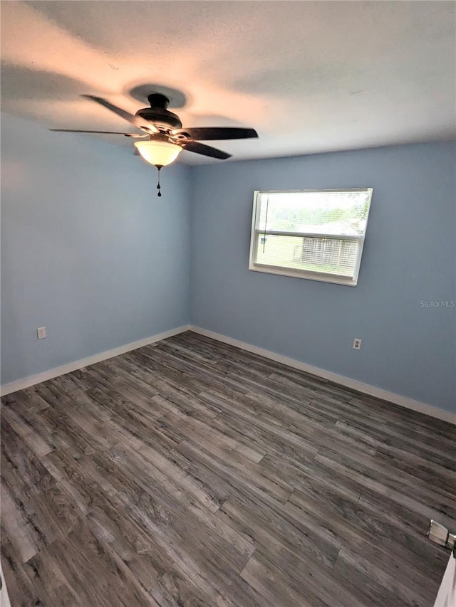 spare room featuring dark wood-type flooring and ceiling fan