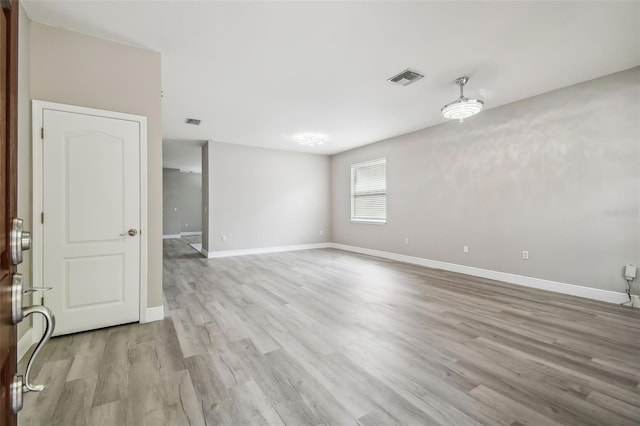 spare room featuring visible vents, light wood-type flooring, and baseboards