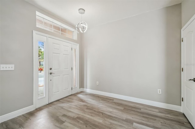 foyer with a notable chandelier, baseboards, and light wood finished floors