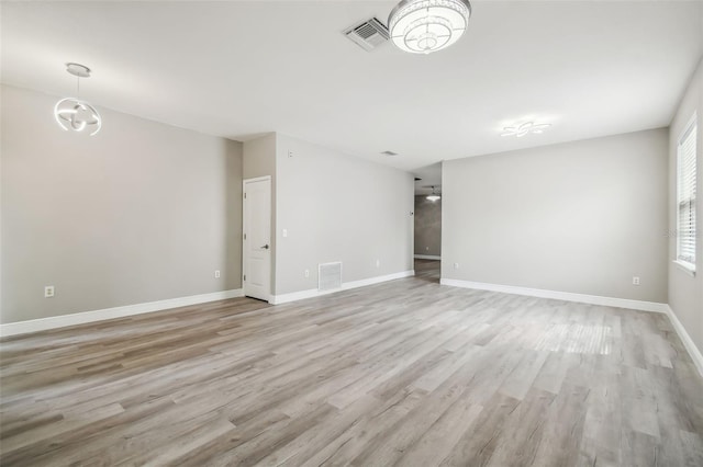 empty room featuring visible vents, baseboards, and light wood-style floors