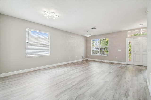 spare room with light wood-style floors, baseboards, and visible vents