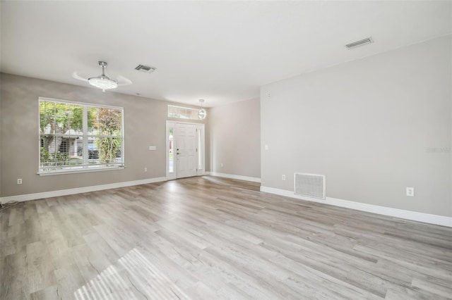 spare room with baseboards, visible vents, and light wood finished floors