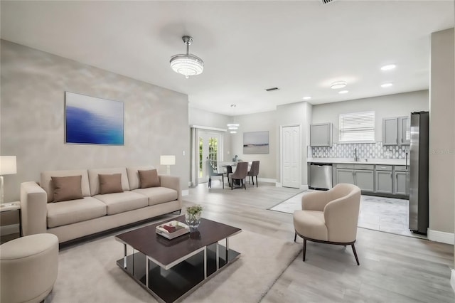 living room with recessed lighting, visible vents, baseboards, and light wood-style flooring