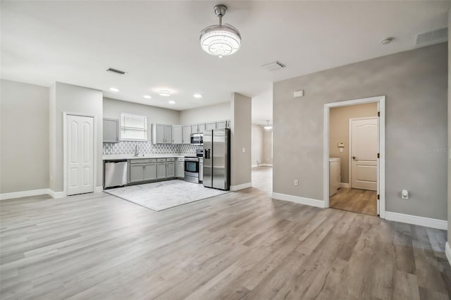 kitchen with visible vents, gray cabinets, stainless steel appliances, light countertops, and tasteful backsplash