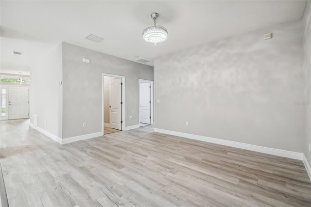 empty room with visible vents, baseboards, and light wood finished floors