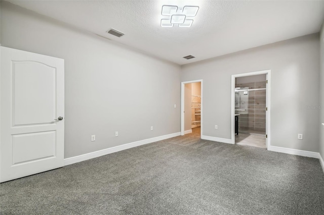 unfurnished bedroom featuring baseboards, visible vents, a textured ceiling, and carpet