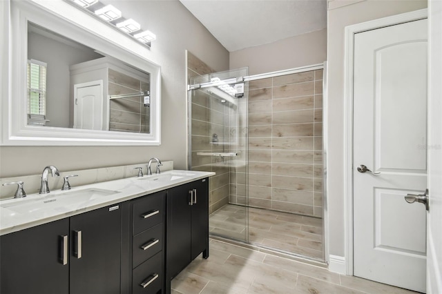 bathroom featuring double vanity, a stall shower, and a sink