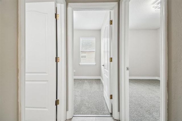 hall featuring baseboards and carpet