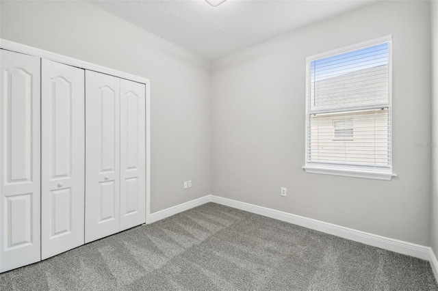 unfurnished bedroom featuring carpet flooring, baseboards, and a closet