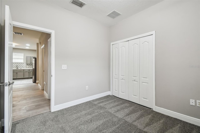 unfurnished bedroom with visible vents and light carpet