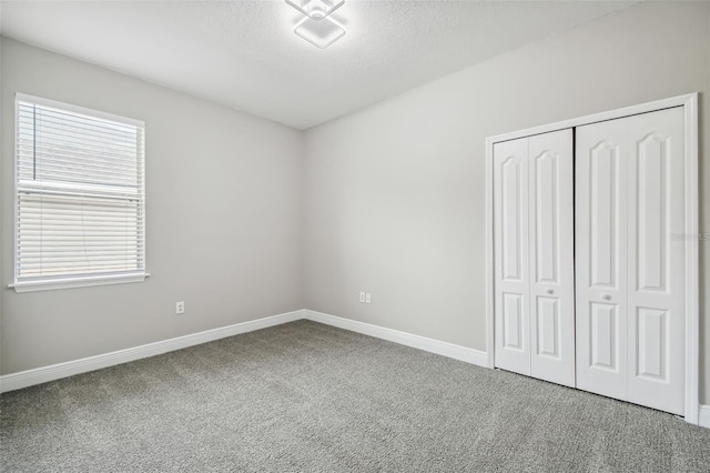 unfurnished bedroom with a closet, baseboards, carpet, and a textured ceiling