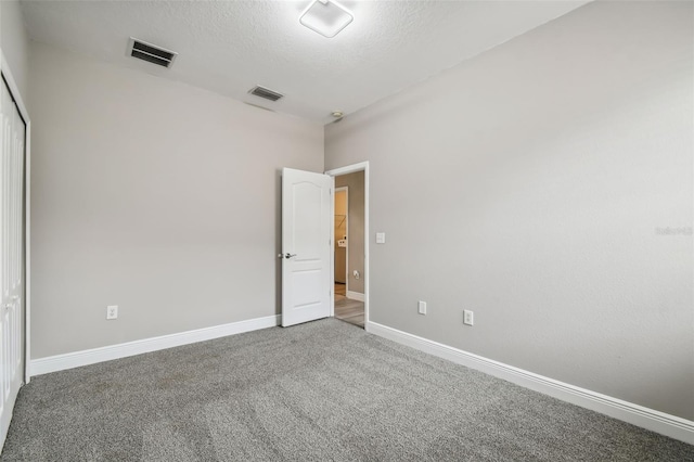 empty room with visible vents, baseboards, a textured ceiling, and carpet flooring