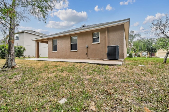 back of house featuring a patio area, stucco siding, a lawn, and central AC