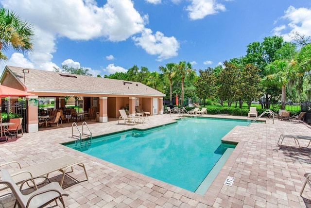 community pool with a patio and fence