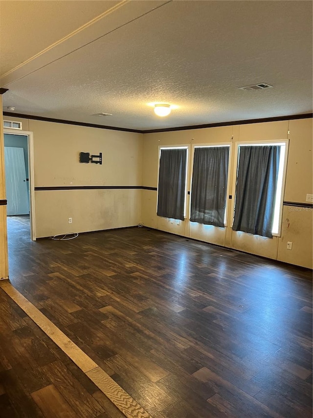 empty room featuring ornamental molding, dark hardwood / wood-style flooring, and a textured ceiling