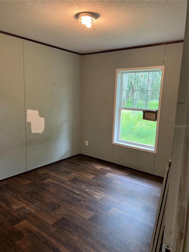 unfurnished room with a textured ceiling, ornamental molding, and dark hardwood / wood-style floors