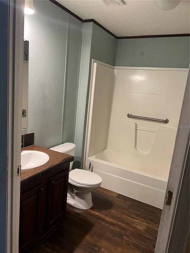 full bathroom featuring a textured ceiling, vanity, toilet, and wood-type flooring