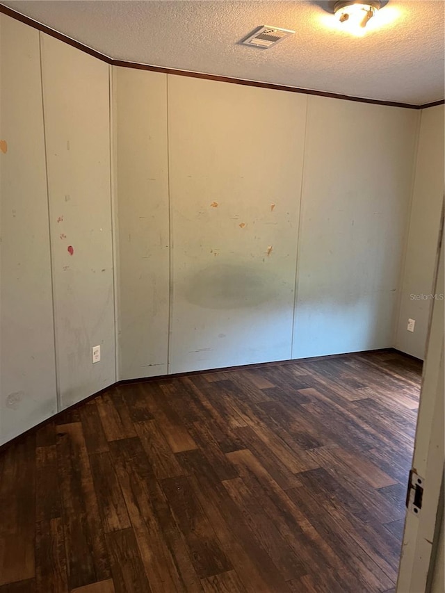 spare room featuring a textured ceiling, crown molding, and dark hardwood / wood-style floors