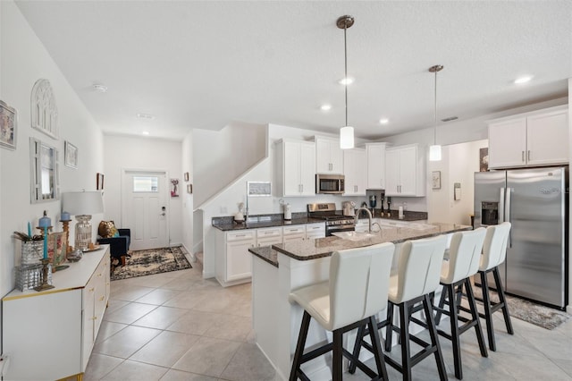 kitchen featuring appliances with stainless steel finishes, a center island with sink, and white cabinets