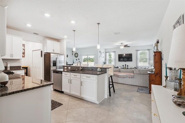 kitchen with hanging light fixtures, dishwasher, sink, ceiling fan, and a kitchen bar