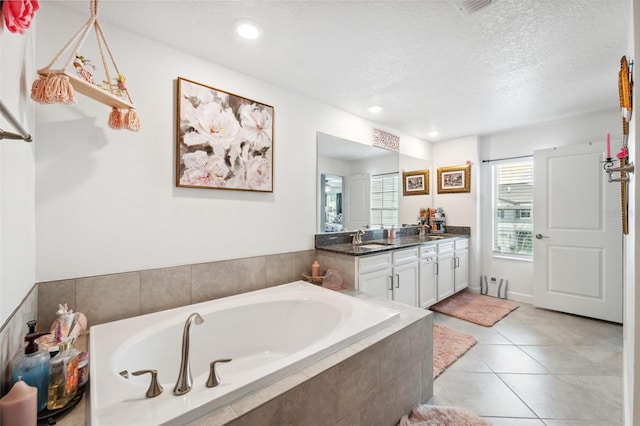 bathroom featuring vanity, a textured ceiling, tile patterned flooring, and tiled bath