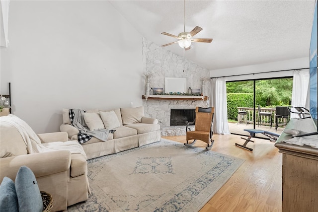 living room with wood finished floors, high vaulted ceiling, a fireplace, ceiling fan, and a textured ceiling