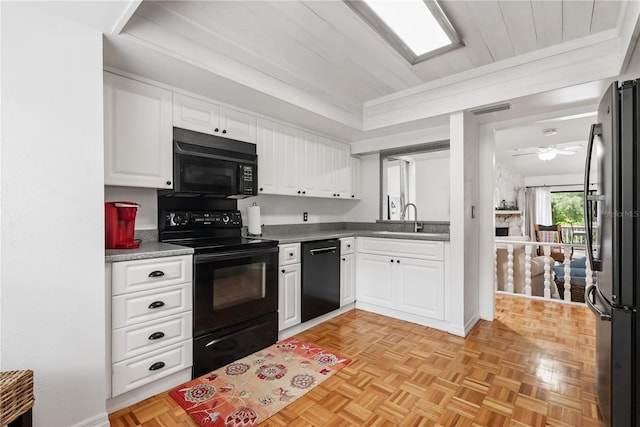 kitchen featuring visible vents, white cabinetry, black appliances, and a sink