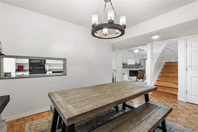 dining room featuring ceiling fan with notable chandelier, light parquet floors, and a textured ceiling