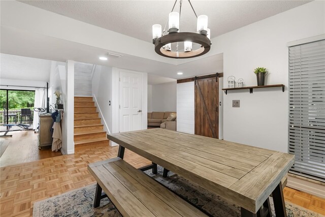 dining area featuring a textured ceiling, a barn door, a notable chandelier, and light parquet floors