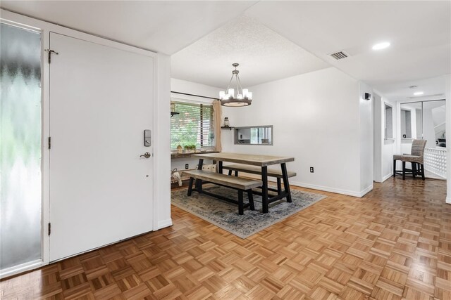 dining room with light parquet flooring, a textured ceiling, and a notable chandelier