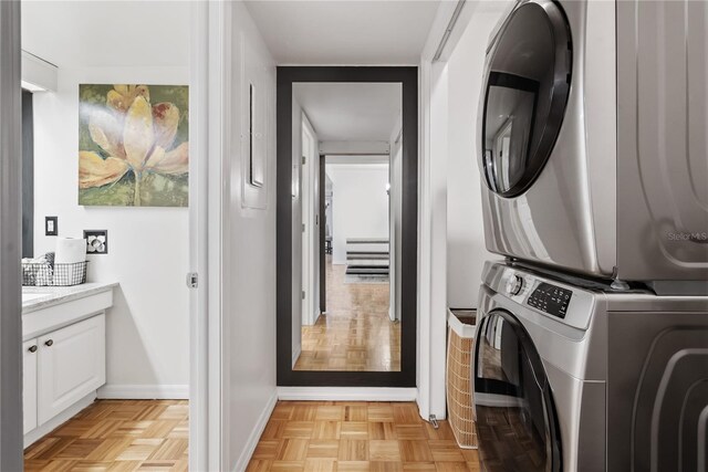 laundry area featuring light parquet floors and stacked washer and clothes dryer