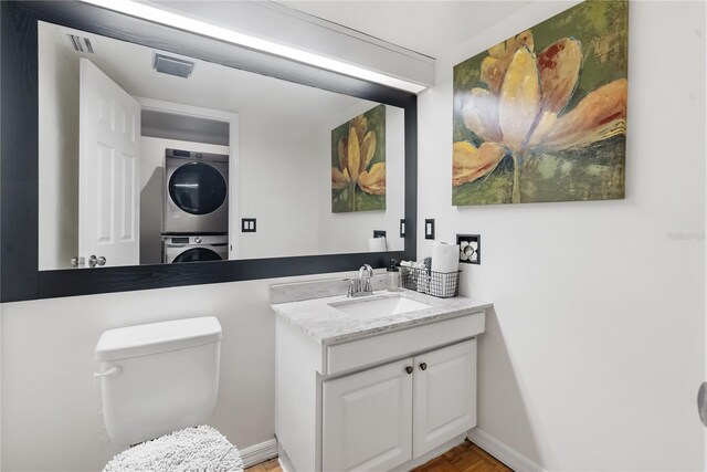 bathroom with vanity, toilet, and stacked washer / dryer