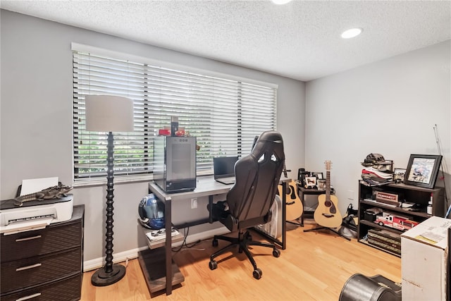 office area featuring baseboards, a textured ceiling, and light wood finished floors