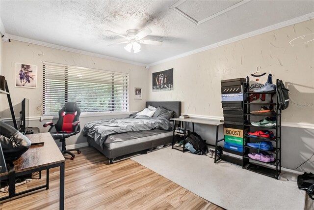 bedroom featuring ceiling fan, hardwood / wood-style flooring, ornamental molding, and a textured ceiling