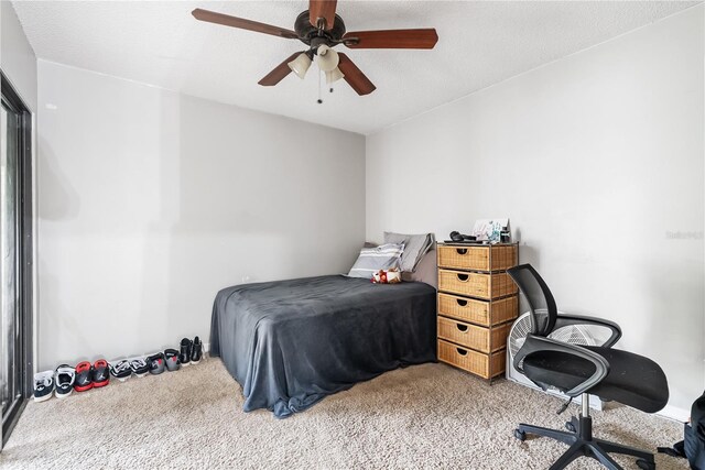 carpeted bedroom with ceiling fan and a textured ceiling