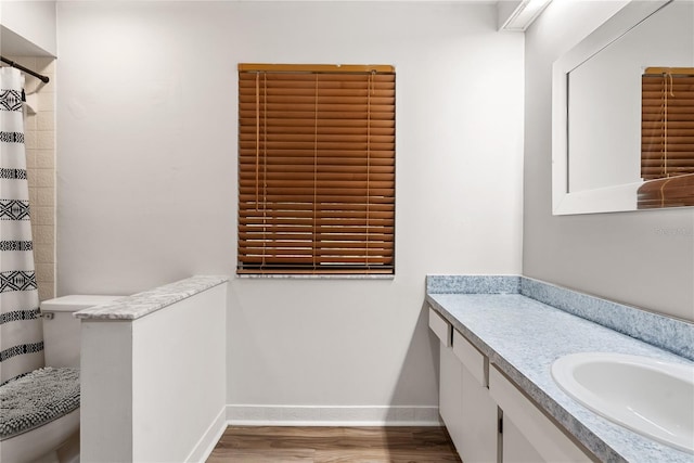 full bathroom featuring toilet, vanity, baseboards, and wood finished floors