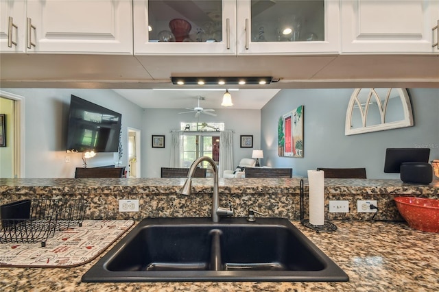 kitchen with white cabinets, ceiling fan, dark stone countertops, and sink