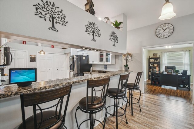 kitchen featuring white cabinets, hanging light fixtures, hardwood / wood-style flooring, and stainless steel fridge with ice dispenser