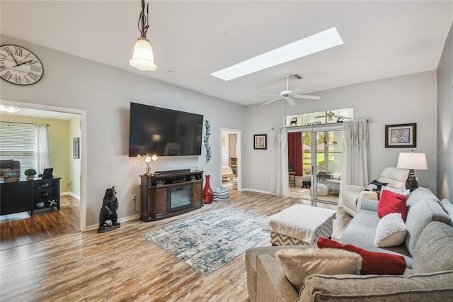 living room featuring ceiling fan, hardwood / wood-style floors, and a skylight