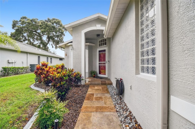 entrance to property with a yard and central air condition unit