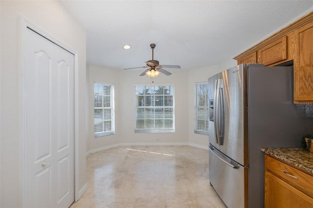 kitchen with stainless steel refrigerator with ice dispenser, ceiling fan, and dark stone countertops