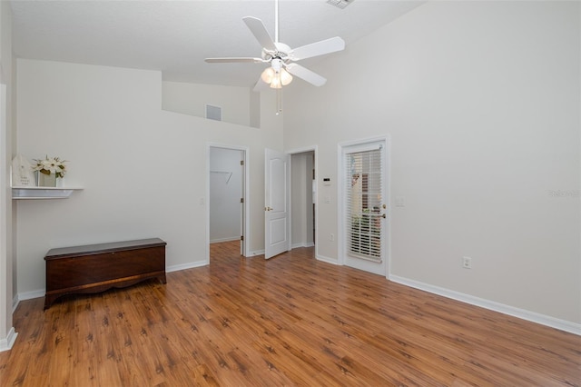 unfurnished bedroom featuring a ceiling fan, wood finished floors, baseboards, and high vaulted ceiling