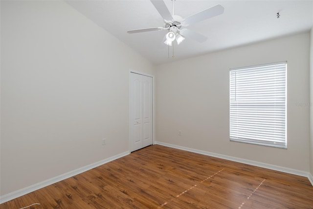 spare room featuring a ceiling fan, vaulted ceiling, wood finished floors, and baseboards