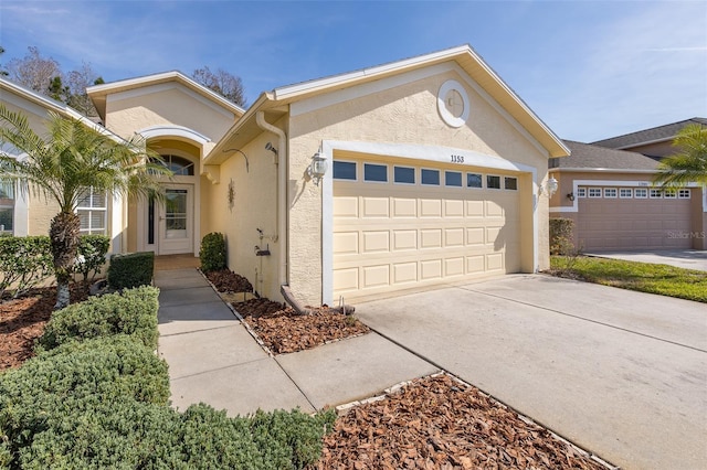 ranch-style house featuring stucco siding, driveway, and an attached garage