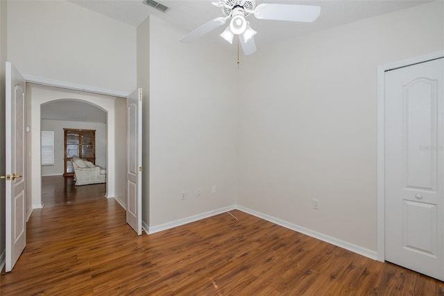 unfurnished room with visible vents, ceiling fan, baseboards, wood finished floors, and arched walkways