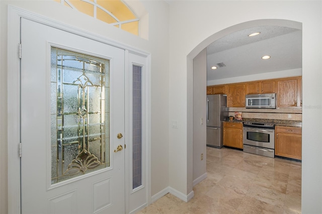 foyer entrance with recessed lighting, visible vents, arched walkways, and baseboards