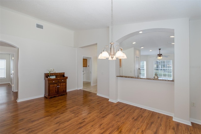 unfurnished dining area featuring sink, wood-type flooring, and vaulted ceiling